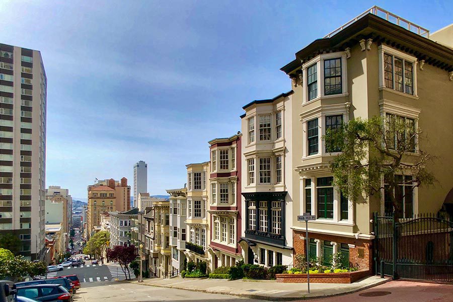 About Our Agency - Residential Street in San Francisco, California, Street Sloping Down a Hill, Skyline in the Distance